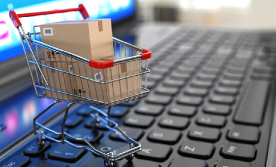 E-commerce. Shopping cart with cardboard boxes on laptop. 3d
