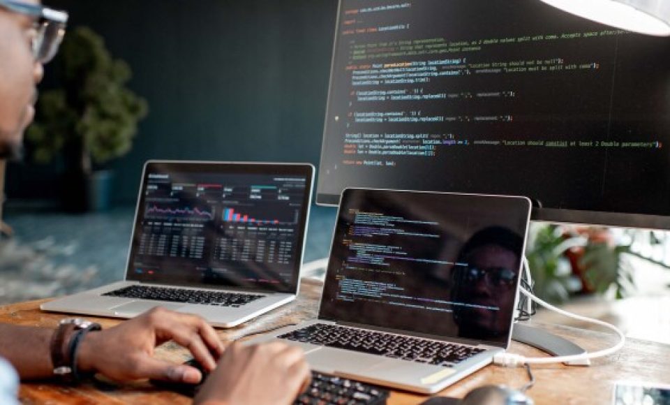 Young african male programmer writing program code sitting at th