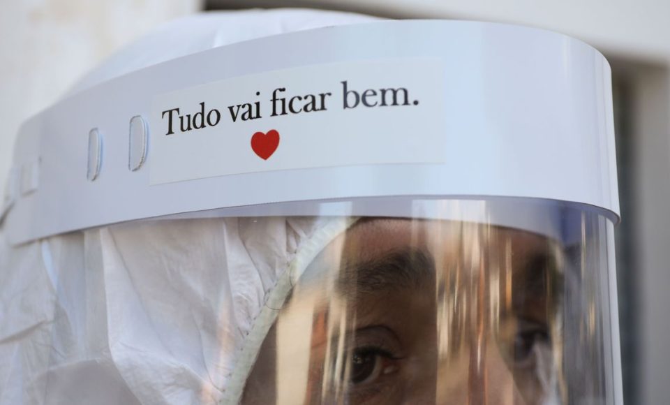 Um trabalhador do Funeral SOS da cidade de Manaus, vestindo roupas de proteção, observa antes de remover o caixão de Amadeu Garcia da Silva, 80 anos, de sua casa, em meio ao surto de doença por coronavírus (COVID-19), em Manaus, Brasil 29 de abril de 2020. A placa diz: "Tudo vai ficar bem".